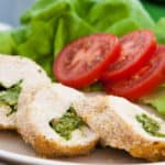 Plakjes kipfilet gevuld met pesto en kaas met een portie sla en tomaat.